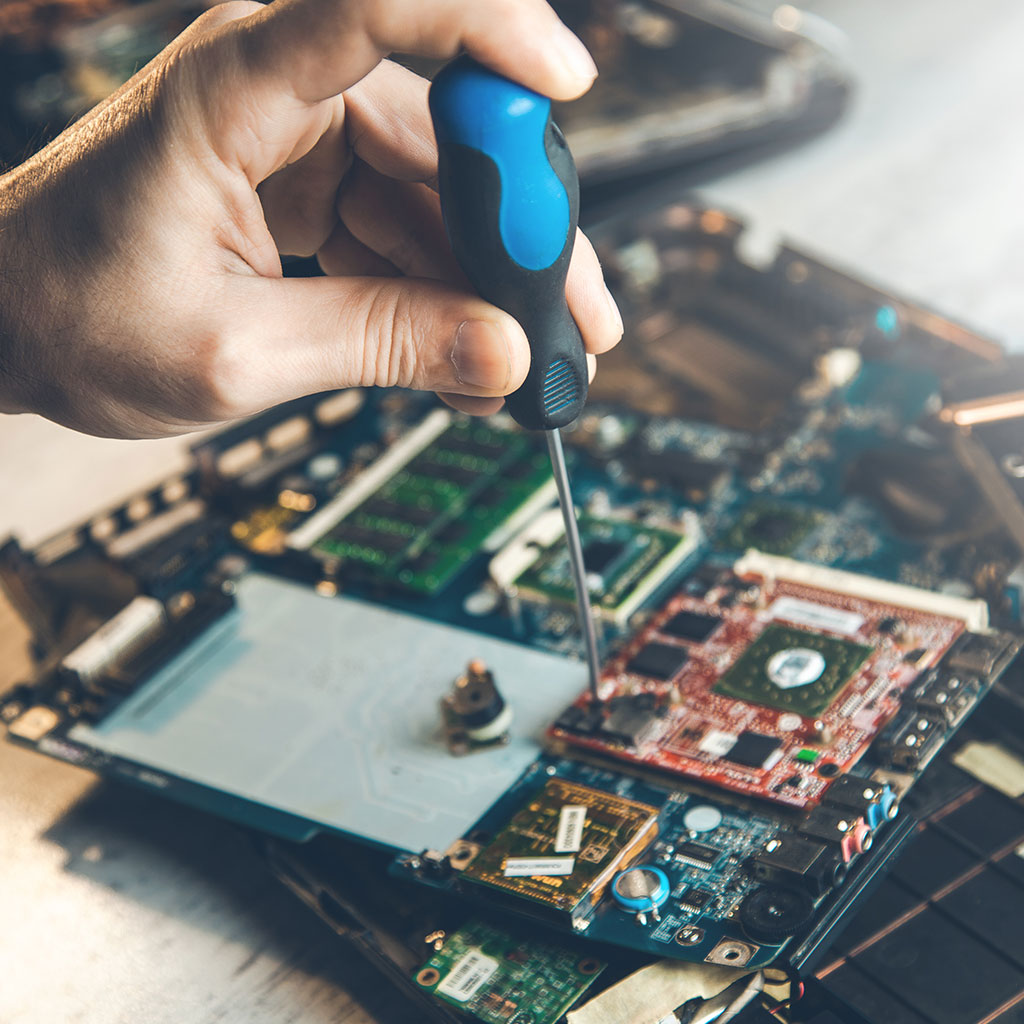 Hand mit Schraubendreher bei der Reparatur einer Elektronikplatine